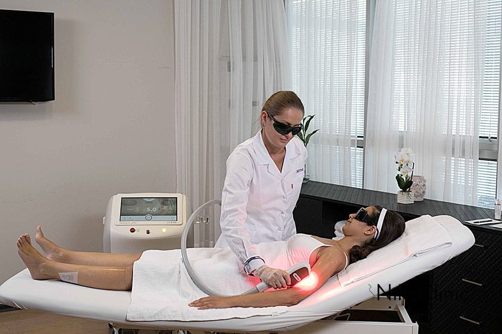 Una donna riceve un trattamento laser Alma Beauty Rejuve sul braccio da un tecnico in una medical spa multitecnologica.